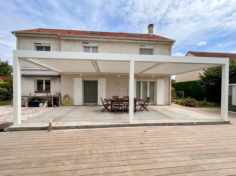 Terrasse extérieure avec pergola bioclimatique à lames orientables en aluminium laqué blanc, structure autoportante fixée en façade