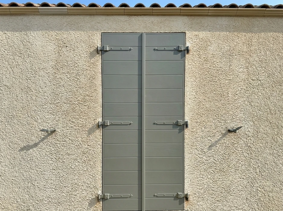Façade extérieure en enduit grésé beige avec volets battants fermés en aluminium gris anthracite, style lisse à lames horizontales
