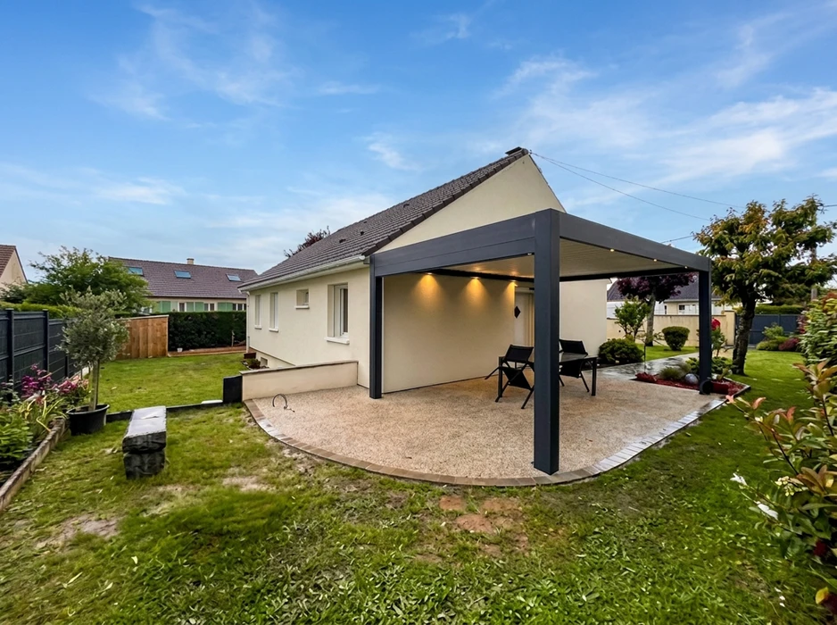 Pergola bioclimatique aluminium anthracite installée en terrasse attenante à une maison pavillonnaire
