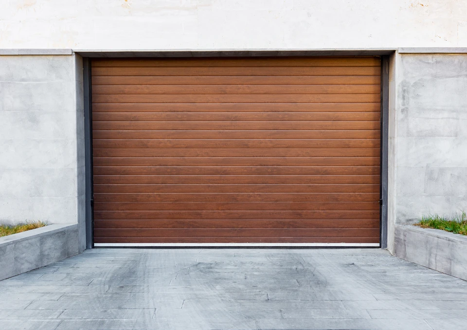 Garage résidentiel moderne en soirée avec porte sectionnelle en cours d'ouverture révélant une voiture blanche garée à l'intérieur