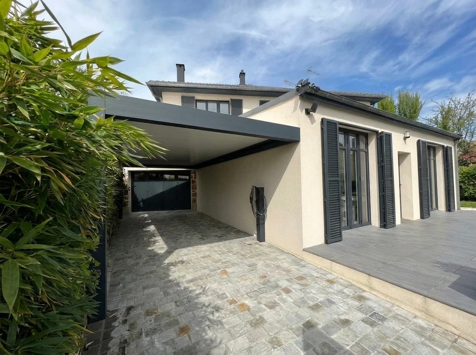 Pergola bioclimatique aluminium anthracite adossée à une façade, avec lames orientables blanches