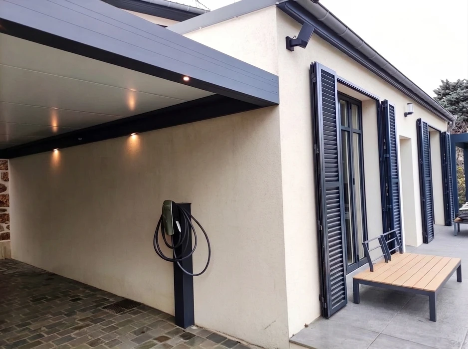 Pergola bioclimatique autoportante en aluminium anthracite, installée en terrasse attenante à un pavillon résidentiel