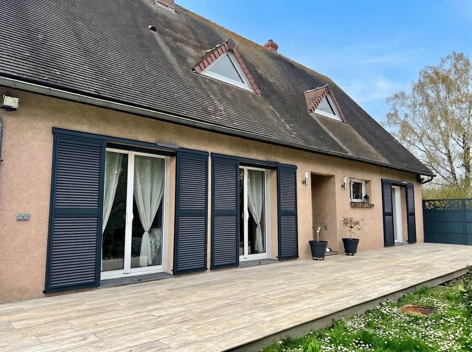 Façade extérieure de bâtiment avec fenêtre équipée de volets battants gris anthracite ouverts et volet roulant blanc fermé