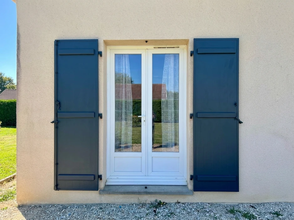 Façade extérieure en enduit grésé beige avec volets battants fermés en aluminium gris anthracite, style lisse à lames horizontales