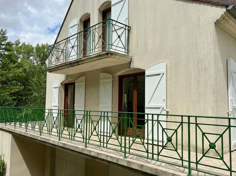Façade extérieure en enduit grésé beige avec volets battants fermés en aluminium gris anthracite, style lisse à lames horizontales