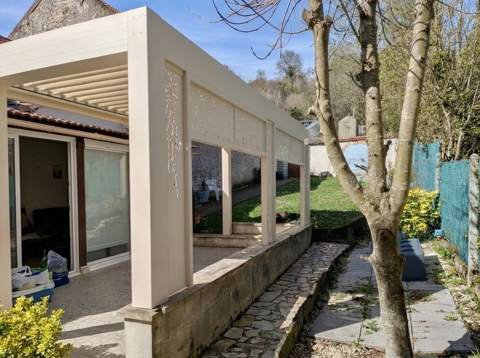 Pergola bioclimatique aluminium anthracite installée en terrasse attenante à une maison pavillonnaire