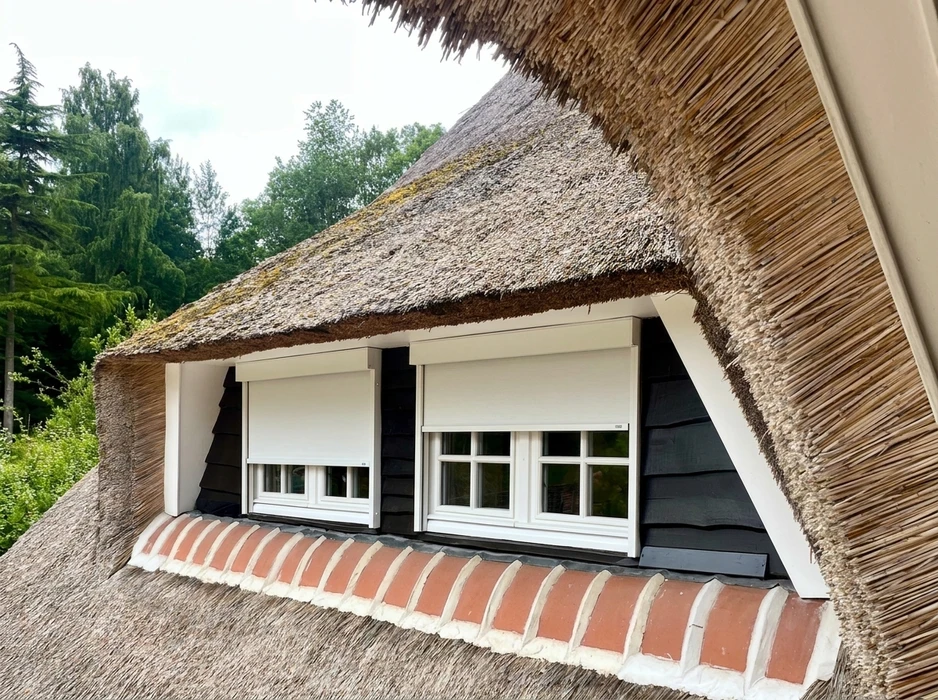 Pergola bioclimatique aluminium anthracite adossée à une façade, avec lames orientables blanches
