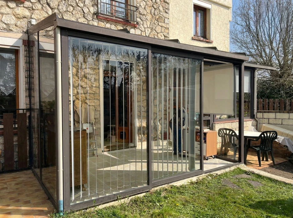 Pergola bioclimatique autoportante en aluminium anthracite, installée en terrasse attenante à un pavillon résidentiel