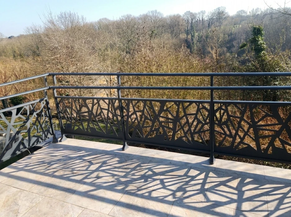 Terrasse couverte vue de l'intérieur, pergola bioclimatique à lames orientables en aluminium blanc, position ouverte laissant apparaître un ciel bleu nuageux