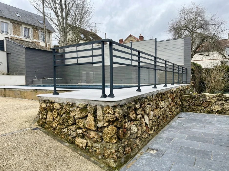 Terrasse couverte vue de l'intérieur, pergola bioclimatique à lames orientables en aluminium blanc, position ouverte laissant apparaître un ciel bleu nuageux